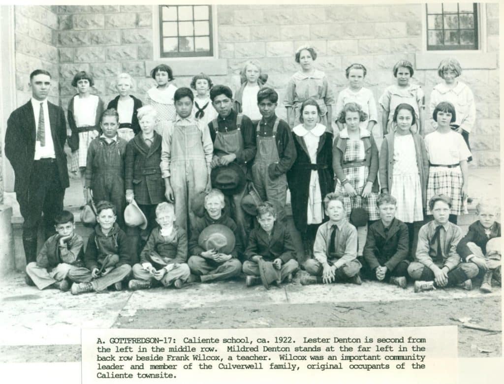 A 1922 black and white photo shows a group of 28 students and a teacher in front of a brick building.