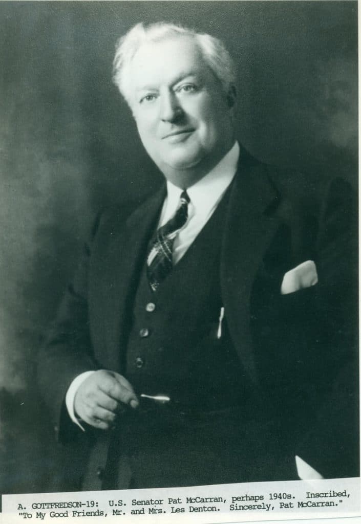 A smiling man in a suit and plaid tie holds a small object, with text "U.S. Senator Pat McCarran."