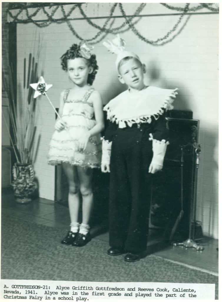 A young girl in a fairy costume holds a star wand next to a boy in a ruffled clown suit.