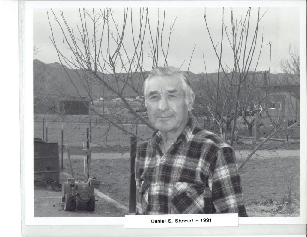 A black and white photo of a man in a plaid shirt, "Daniel S. Stewart - 1991" below him.