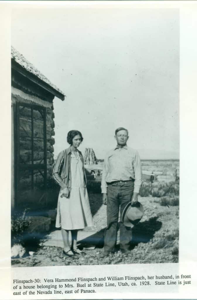 A black and white photo shows a woman and man standing outside a stone building.
