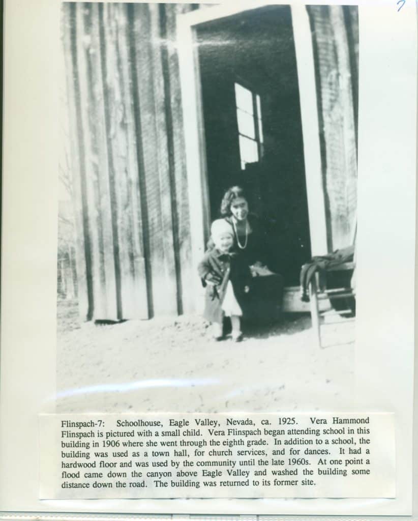 A woman with a pearl necklace and a small child stand in a dark doorway with a window reflecting light.