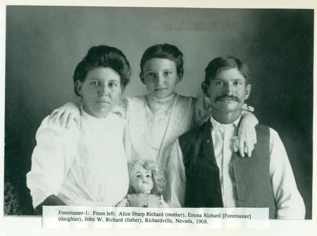 A black and white photo shows a family of three and a doll, with text "Foremaster-1: From left: Alice Sharp Richard (mother), Emma Richard [Foremaster] (daughter), John W. Richard (father), Richardville, Nevada, 1908."