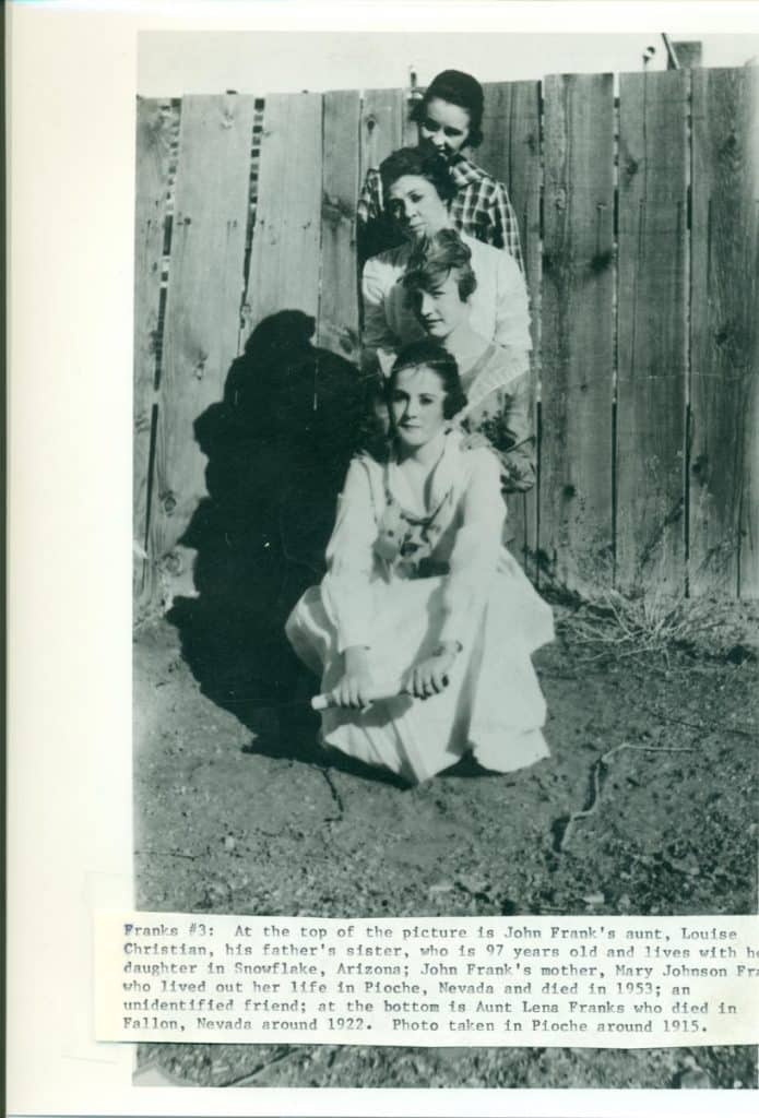 Four women of varying ages stand in a line against a wooden fence, with one woman crouching in front.