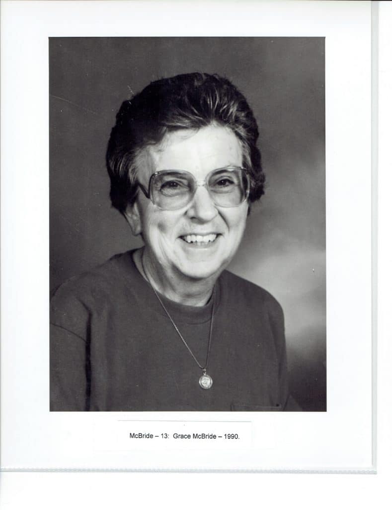 A smiling woman with short, dark hair and glasses wears a necklace; "McBride - 13: Grace McBride - 1990."