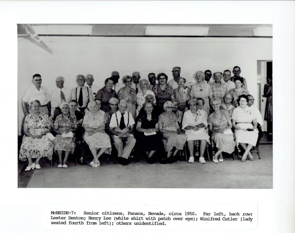 A large group of smiling senior citizens, men standing in back and women seated in front, face forward.