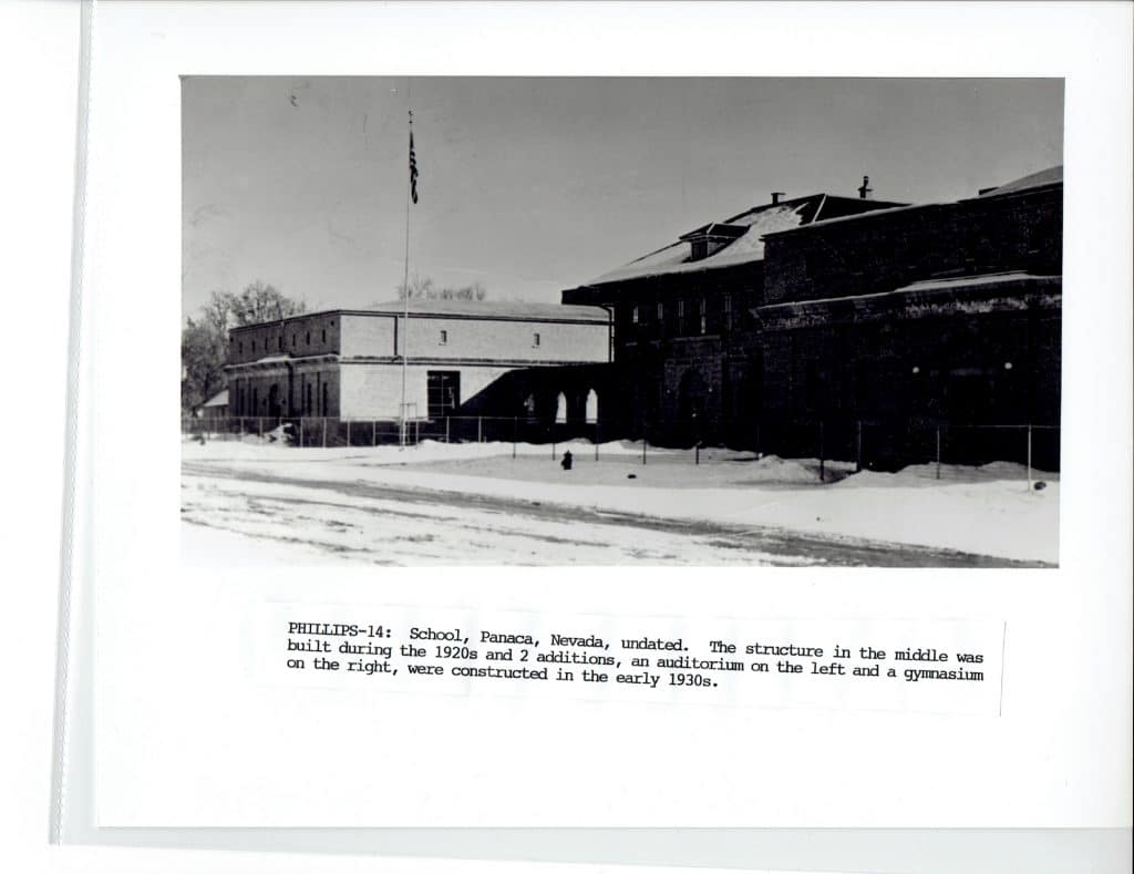 Black and white photo of a snow-covered school building with a flagpole, "PHILLIPS-14" text below.
