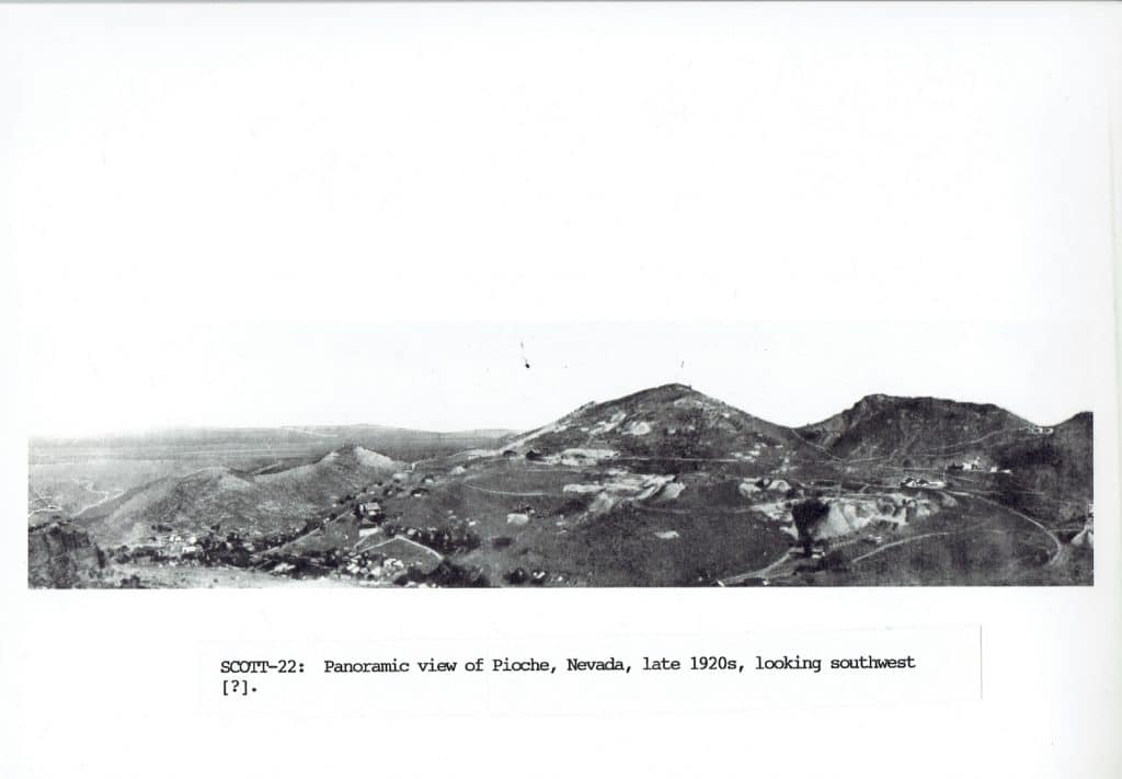 Black and white panoramic photo of a mining town nestled in rolling hills with text "SCOTT-22: Panoramic view of Pioche, Nevada, late 1920s, looking southwest".