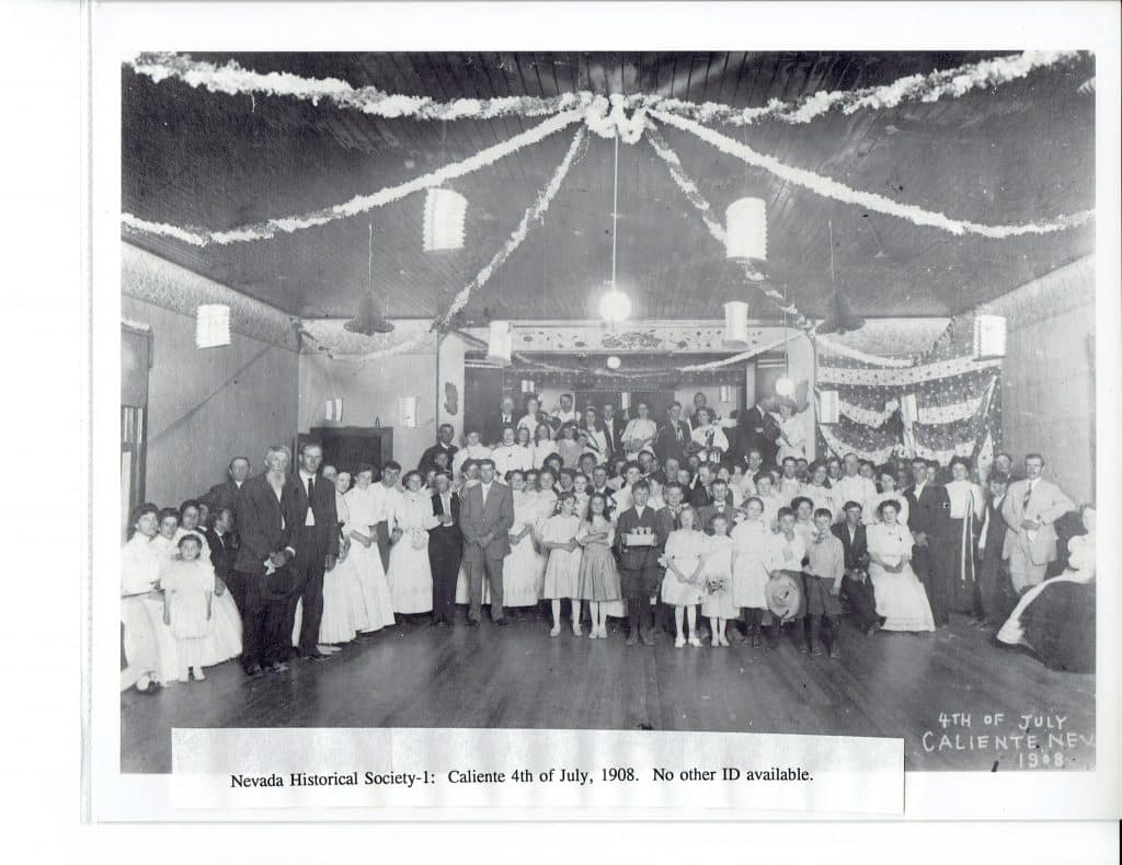 A large group of people, including men, women, and children, pose in a decorated hall.