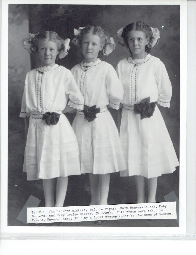 Three young girls in white dresses with dark bows stand side-by-side, "Lee #1: The Danvers sisters...about 1917."