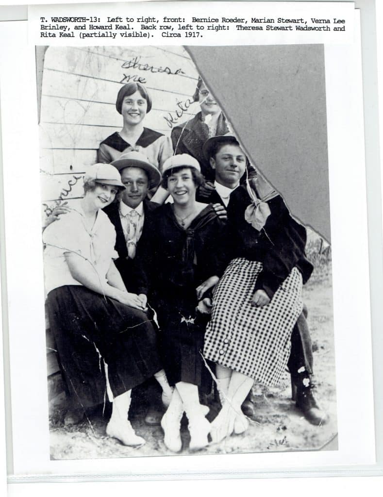 Seven young adults, four women and three men, pose for a black and white photo in 1917.