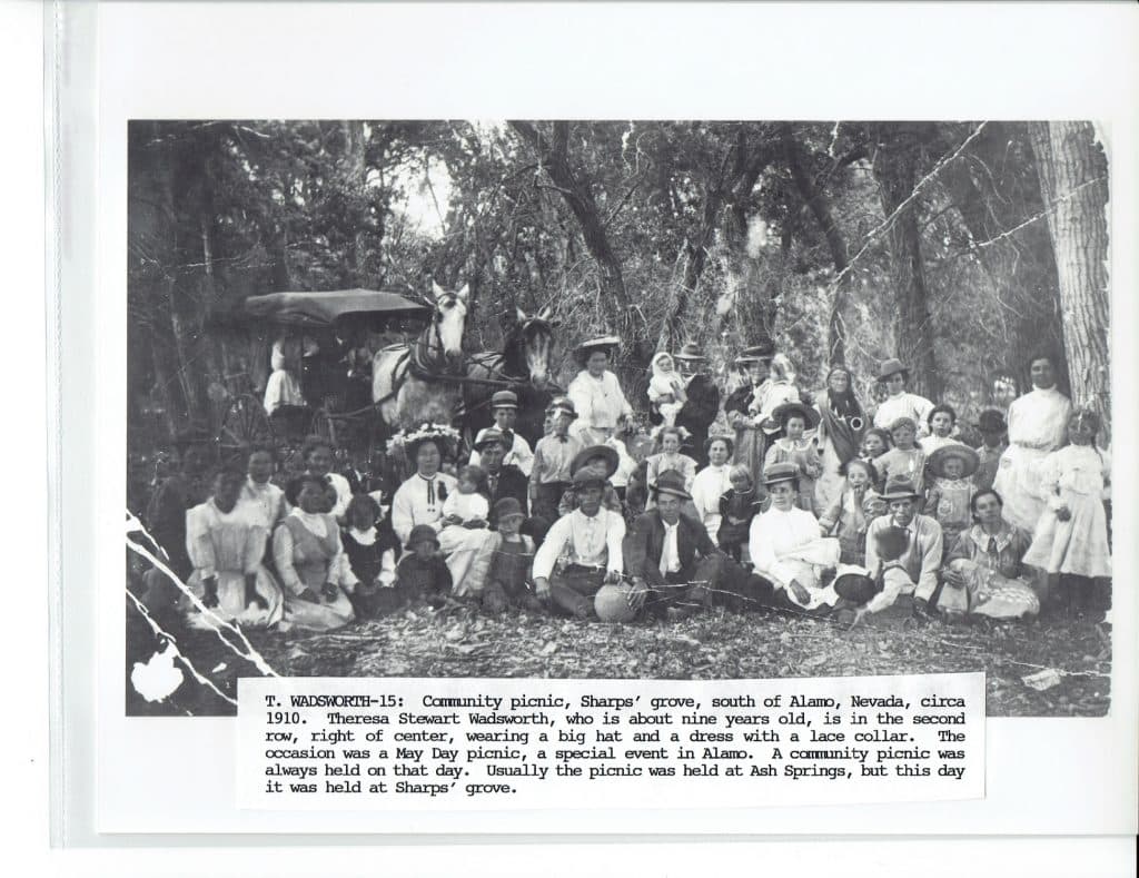 A large group of people, including adults and children, pose for a photo with horses and a carriage.
