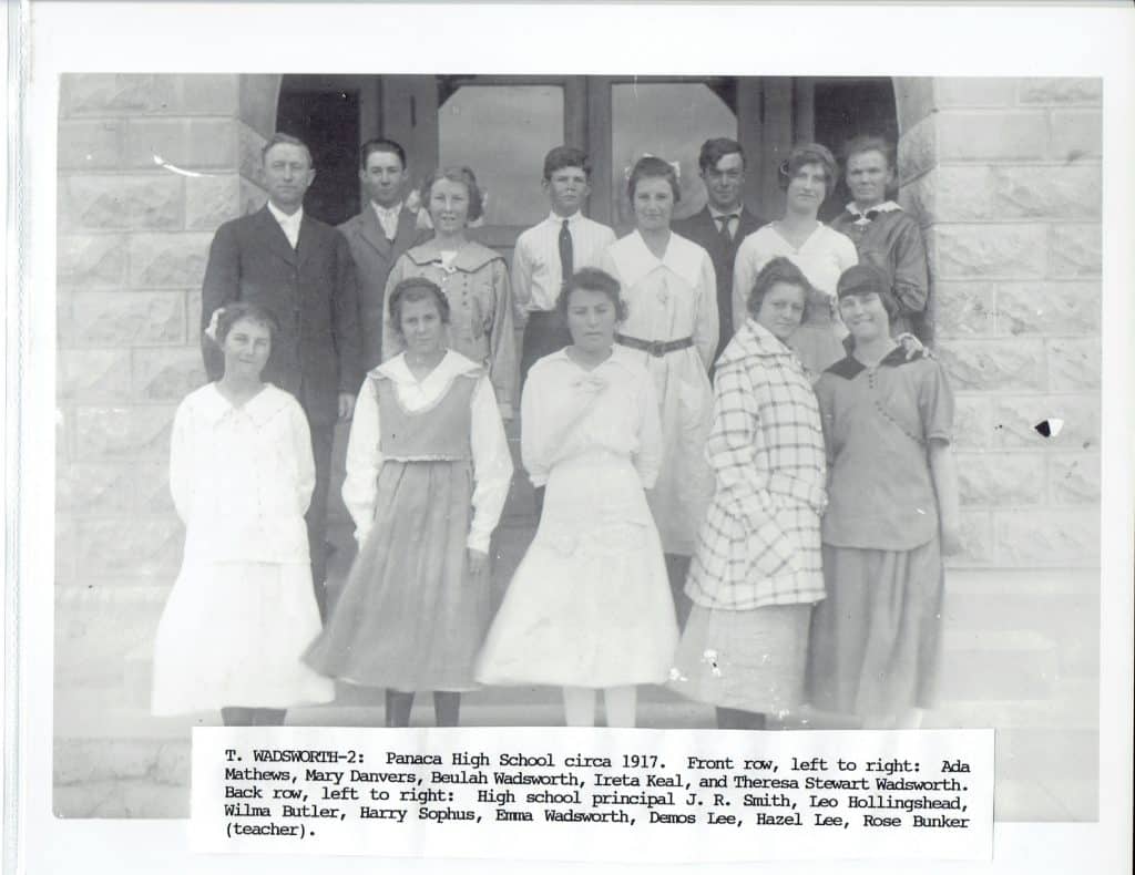 A black and white photo shows 15 students and a teacher posing on stone steps, with text below.
