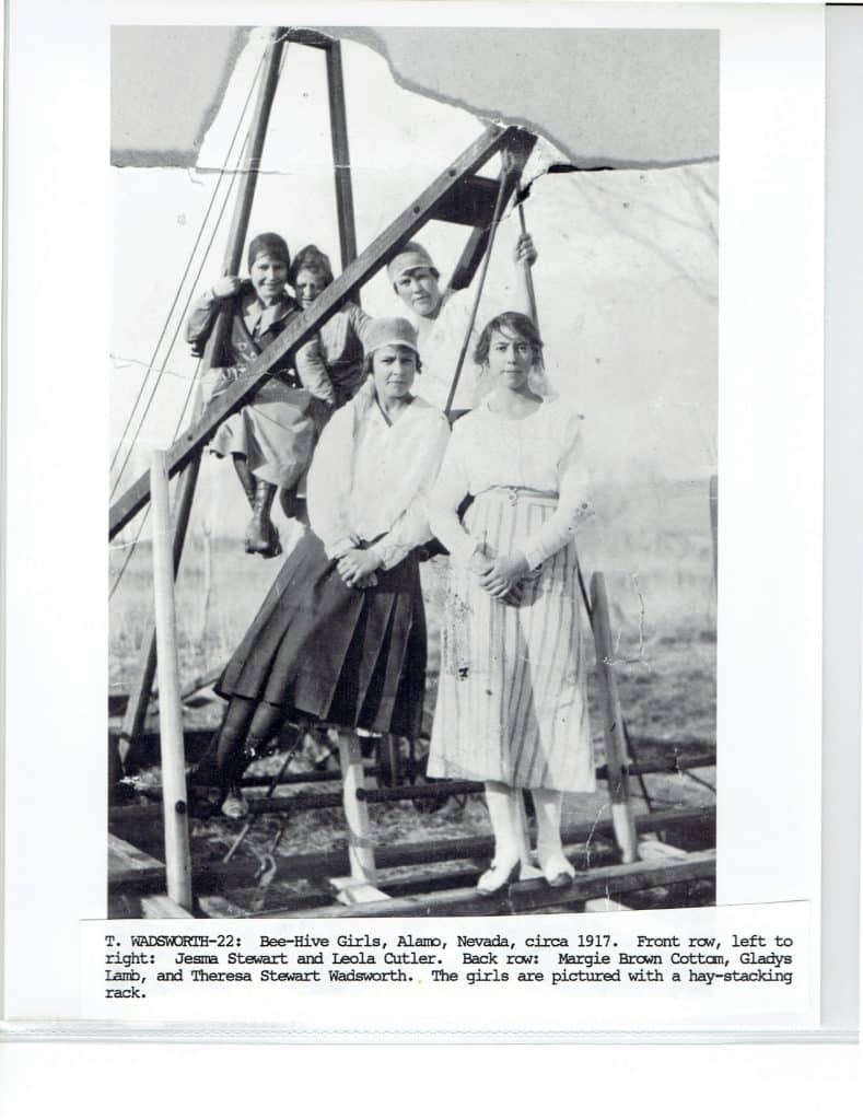 Six young women pose on and around a wooden hay-stacking rack, with descriptive text below.